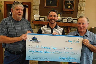 Jameson Hanson, owner of AF Running Tiger (Anytime Fitness), center, accepts a check representing a $50,000 loan from the city of Stewartville's revolving loan fund. Anytime Fitness will pay off the loan at 3.25 percent interest for 10 years. The business will use the funds to purchase equipment for its relocation to an 8,000 square-foot space at 1600 Second Ave. Northwest, Stewartville. Jim Kuisle, president of the city of Stewartville's Economic Development Authority (EDA), left, and Mayor Jimmie-John King present the check at the EDA's regular monthly meeting on Tuesday, Aug. 17.
