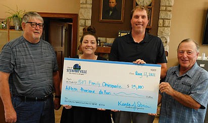 Dr. Kevin Hosch and his fiancee, Theresa Gehling, of 507 Family Chiropractic, accept a check representing a $15,000, no-interest, seven-year loan from the city of Stewartville's revolving loan fund. The business will use the funds to purchase equipment for a new chiropractic wellness clinic at 100 Second St. Southwest, Stewartville. Jim Kuisle, president of the city of Stewartville's Economic Development Authority (EDA), left, and Mayor Jimmie-John King present the check at the EDA's regular monthly meeting on Tuesday, Aug. 17.