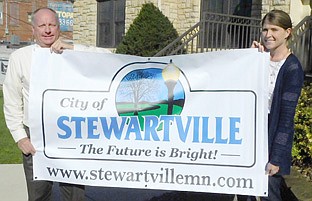 Bill Schimmel Jr.,city administrator, left, and Karla Strain, finance director, both of whom work with the city's Economic Development Authority, display a new city of Stewartville sign the EDA plans to display at a variety of events, including, for example, the annual Rochester  Area Builders Home Show.