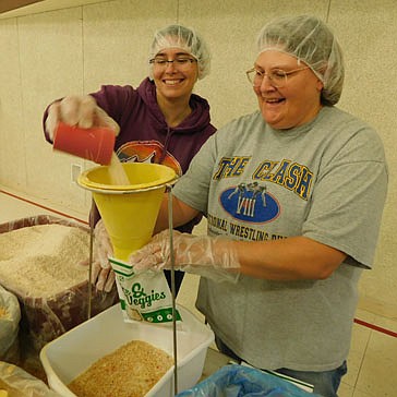 Ruth Goodsell of Stewartville, a member of Grace Evangelical Free Church, left, pours ingredients through a funnel and into a bag held by Liza Neseth, who also attends Grace Church, at the meal pack for Haiti at the Church gym on Saturday, Oct. 30. Volunteers packaged a total of about 57,000 meals.