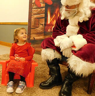 Scarlett Dulek, 3, of Stewartville, smiles brightly at Santa Claus as she prepares to share her Christmas wish list at the Stewartville Kiwanis Club's Visit With Santa at the Stewartville Civic Center on Saturday morning, Dec. 4. Children from more than 60 families met with Santa that day.
