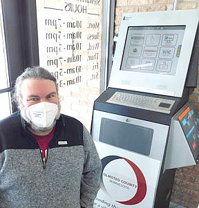 Nate Deprey, director of the Stewartville Public Library, poses near the kiosk located at the Library's entrance. The kiosk offers a wide variety of Olmsted County Services for residents who would prefer to avoid a trip to Rochester.