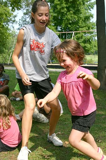 Gabi Hale, left, a Tiger Time volunteer, reaches to catch Maya Ramp, 4 1/2, of Stewartville, during a game of "Duck, Duck, Gray Duck." 