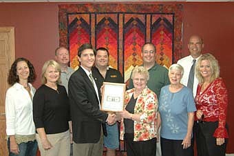 WELCOME TO STEWARTVILLE -- The Stewartville Area Chamber of Commerce welcomed "All in Stitches" to the local business community with an official ambassador visit last week. Jarett Jones, president of the Chamber, third from left, presents Sandy Evans, owner of the new quilting and fabrics store, with a "first dollar earned" plaque.  Chamber of Commerce members who were on hand for the occasion included, front row, from left, Jodi Beck, Chamber administrator; along with Earlene Wickre of All in Stitches, Jan Lubahn and Beth Schmidt. Back row, from left, Bill Schimmel Jr., Monte Beck, Greg Schimek and Rick Jaacks.                                                          