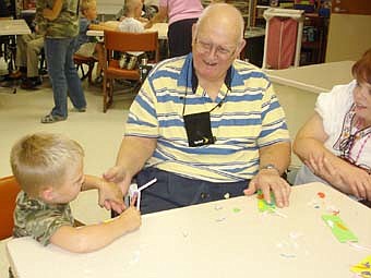 The Preschool II class from Endless Journey Child Care visited the Stewartville Care Center Sept. 24 and assisted residents with an art project,  making  bookmarks. They also sang for the residents and handed out flowers. Pictured above Allen Jorgensen, resident, chats with Tarin Conlin from the child care. Far right is Pat Lorenz from the Activity Department. 
