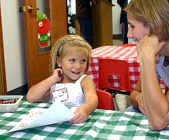 Ella Quam, 3, of Stewartville, smiles while working on an art project as she looks toward her mother, Lisa Quam.  Wee Care welcomed almost 120 students back to school this fall, a near-record number. 