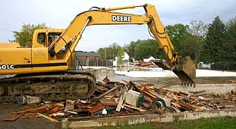 A backhoe clears the debris of the bath house at the site of the old pool. 
