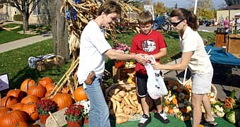 THE DELIGHTS OF AUTUMN -- Although the weather felt more like July, hundreds of shoppers enjoyed the annual Fall Harvest Day at the parking lot near Stewartville City Hall on a warm and windy Saturday, Oct. 6. Here, Jean Hoth of Stewartville, right, and her 9-year-old son Brandon purchase gourds from Roberta Beaver, a leader of the Racine Ramblers 4-H Club. 