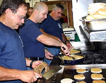 GOOD COOKS -- The Stewartville Fire Department hosted its annual fund-raising pancake breakfast at the Stewartville American Legion Post 164 on Sunday, Oct. 7. As firefighter Steve Lawson, left, flips the pancakes, firefighters Vance Swisher, center, and Mark Podein, right, mix the scrambled eggs.  Steve Wolf, fire chief, said that almost 900 people attended the event. 
