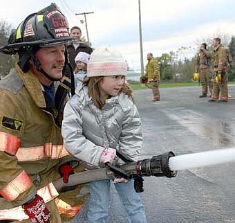 Braving temperatures in the 40s, hundreds of Stewartville and area residents attended the Stewartville Fire Department's annual open house on Wednesday, Oct. 10.  In a popular annual event, firefighter Jim Elliott helps Jaidyn Brower, 5, operate the fire hose. 
