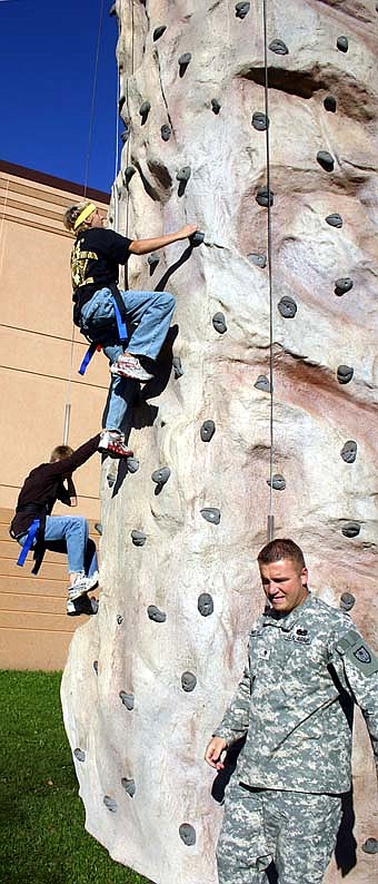 SCALING THE WALL -- Jon Weigel of the Army National Guard, foreground, supervises as two Stewartville High School freshmen climb the Army National Guard's 25-foot high wall. 
