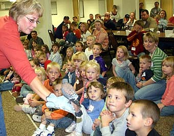 WATCH THE BIRDIE -- Sue Shockey, program coordinator at Rochester's Quarry Hill Nature Center, displays an American kestrel, the smallest falcon in North America, to a group of children at the annual St. John's Wee Care potluck supper last Tuesday, Oct. 16. Shockey also displayed a fox snake. 