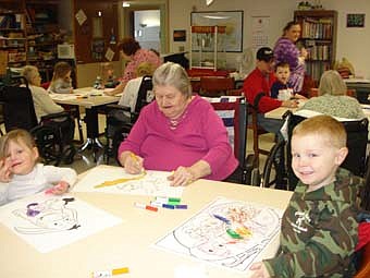 Care Center resident, Dorothy Fuller, colors a picture with Molly McCue and Cole Ramaker from Endless Journey Child Care.  