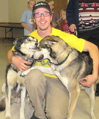 Brent Sass poses with and accepts warm greetings from two of his dogs, Silver and Scroggie, before speaking to a large audience at the Stewartville Civic Center last October. 