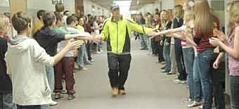 Jim Parry, a sixth-grade teacher at Stewartville Middle School, accepts handshakes from students as he begins his "Mr. Parry's Endurance Challenge" along a Middle School hallway last Thursday, April 19. Running and walking in a cold rain, Parry completed 46 miles in 13 hours.  
