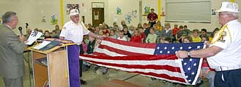 The Stewartville American Legion Post 164 visited Bonner Elementary School on Friday afternoon, Nov. 2, speaking to the third-graders about the importance of community service and respecting the American flag. Here, Dave Nystuen, Bonner Elementary School principal, far left, announces the steps in properly folding an American flag as Don Lyman, left, and Wayne Freiheit, of the Stewartville American fold the flag. 
