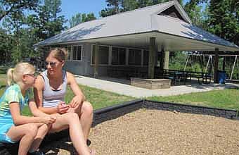 Rachel Beaver of rural Racine, right, talks with Ana Walter, 9, also of rural Racine, as the two sit near the Florence Park shelter on a beautiful morning last Tuesday, June 19.  Beaver, Ana's babysitter, said that the two decided to spend some time in Stewartville last week.  The shelter is undergoing a $50,000 facelift. 