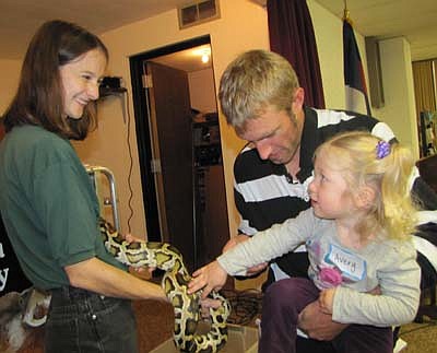 Avery Nelson, 1 1/2, of Stewartville, held by her father Zach, touches a snake held by Melissa Pastika of the RAD Zoo of Owatonna at St. John's Lutheran Church last Monday, Oct. 8.   