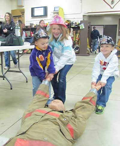 From left, Isaac Algyer, 4; Payton Dahle, 7; and Conner Algyer, 6, all of Rochester, work on dragging a mannequin at the Stewartville Fire Fighters Open House at the Stewartville Fire Hall last Wednesday evening, Oct. 10. Hundreds of Stewartville and area adults and children attended the event.       