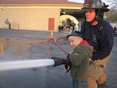 Ty Wilcox, 5, a kindergartner at Bonner Elementary School, uses the water hose under the watchful eye of firefighter Jim Elliott at the annual Stewartville Fire Fighters Open House last Wednesday, Oct. 10. 
