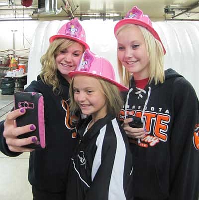 From left, KaitLyn Higgins, 17; and her sisters Madasyn, 11; and Lauryn, 15; all decked out in fire hats, take a photo of themselves at the Stewartville Fire Fighters Open House at the Stewartville Fire Hall last week.    