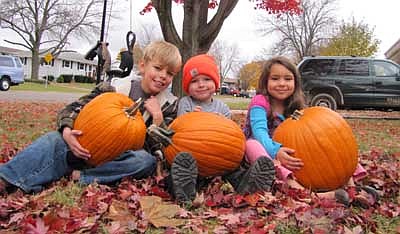 Seated on a bed of leaves, from left, Nathanael Biffert, Ethan Thielen and Littia Biffert enjoy a cool autumn afternoon at the Bifferts' Fifth Avenue Southeast home last Thursday, Oct. 18. Ethan is Nathanael's and Littia's cousin. 