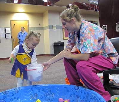 Camryn Klar, 2, of Stewartville, dressed as a cheerleader, selects a prize from a bucket held by Kristen Conley, a senior and a member of the SHS&#8200;Key Club