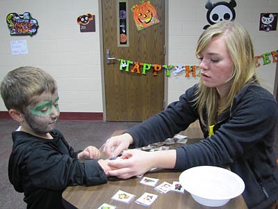 Taylor Zea, a member of the Key Club, applies a Halloween tattoo to Shea Shoemaker, 5, a Bonner kindergartner