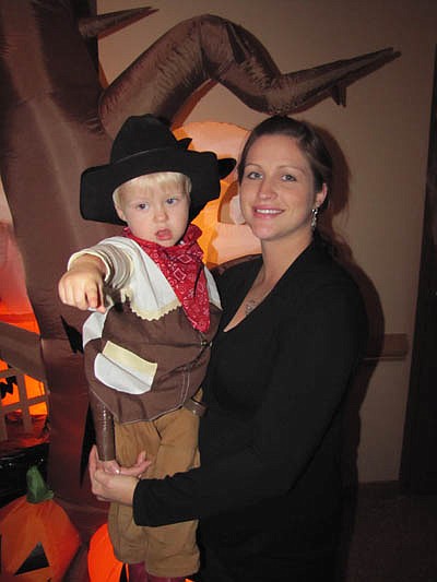 Dana Norby of Stewartville holds her son Ben, 2, who came to the party all decked out as a cowboy.     