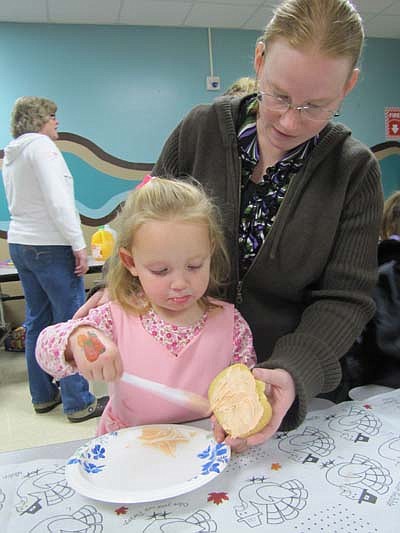 Hollie Phillips of Sparta, Wis., helps her daughter Sarah decorate a pumpkin cookie