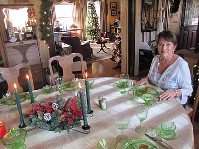 Liz Howe sits at her dining room table, which is adorned with green depression dishes she received from her grandmother years ago. She says she consented to include her house in this year's Christmas on Display House Tour in honor of her late husband Ken, who made the house what it is.  