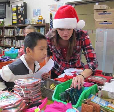 Tina Gordon, a coordinator of the BACPAC Santa Shop, helps Nick Dong, a second grader at Bonner Elementary School, look for gifts at the Santa Shop last Thursday, Dec. 6. After students, parents and others bring box tops and bottle caps to school, BACPAC members send the items to Kemps or Kwik Trip, which respond with reimbursement checks. The money pays for Santa Shop items, field trips and more.  