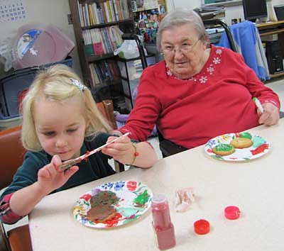 Stephanie Svoboda, 3, of Stewartville, left, is part of a group of home-schooled children that decorated cookies with the residents of the Stewartville Care Center last week. Lois Terry, a resident of the Care Center, looks on at right.