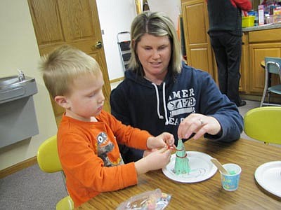 Caden Nagel, 3, of Stewartville, a student in a parent-child class with Stewartville Early Childhood Family Education (SECFE). celebrated the Holiday Fun Night at the Early Childhood Learning Center last Thursday, Dec. 13 by decorating a ice cream cone Christmas tree with help from his mother, Katie.  