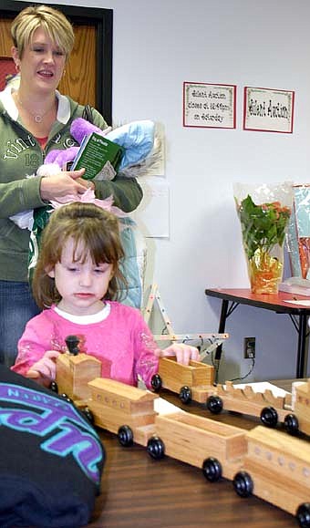 SHOPPING FOR CHRISTMAS -- Maggie Petersen, 3, of Racine, who attended the annual Wee Care One-Stop Christmas Shop on Friday, Nov. 16 and Saturday, Nov. 17., plays with a model train as Lisa Petersen, Maggie's mom, looks on.  