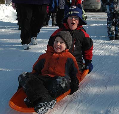 Thomas Meyer, seated in front, and Karsten Ernste, kindergartners in Jen Oelkers' class, smile as their sled begins to gain downward momentum. 