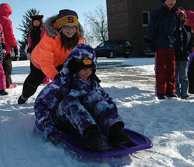 fourth-grader Grace Sveen pushes as Jeena Curry looks forward to her trek to the bottom of the hill. 
