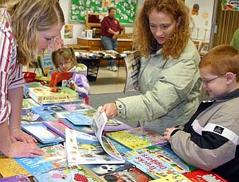 SHOPPING FOR CHRISTMAS -- Nichol O'Neill of Stewartville, above left, sold a variety of books at the Usborne Books booth at the annual Wee Care One-Stop Christmas Shop on Friday, Nov. 16 and Saturday, Nov. 17. Usborne offers educational books for people of all ages, especially those of high school age and under. Kim Mullenbach and her daughter Kylee, 5, a kindergartner at Bonner Elementary School, and son Ridley, 8, a Bonner second-grader, reviewed the books for possible purchase. 