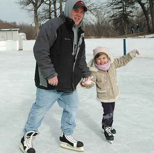 David Davidson and his 5-year-old daughter, Kylie Charmaine Davidson, who live in southwest Stewartville, visited the Florence Park Hockey Rink on Saturday morning, Jan. 26. Supported by her dad, Kylie made several laps around the rink as she worked to improve her skating technique. At left, father and daughter smile for the camera. Below, they turn a corner as they make their way around the rink.  Before long, Kylie was skating on her own, although always under her dad's watchful eye.