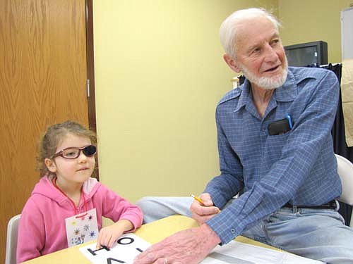 Abigail Langseth, 5, points to the letter "H," which corresponds with the letter she sees on a chart as she gets her eyes tested during Early Childhood Screening at Grace Evangelical Free Church last Tuesday, Feb. 5. Roy Gisler of Stewartville reviews Abigail's progress. Children were tested for hearing and vision, speech and language, and motor skils and concepts.