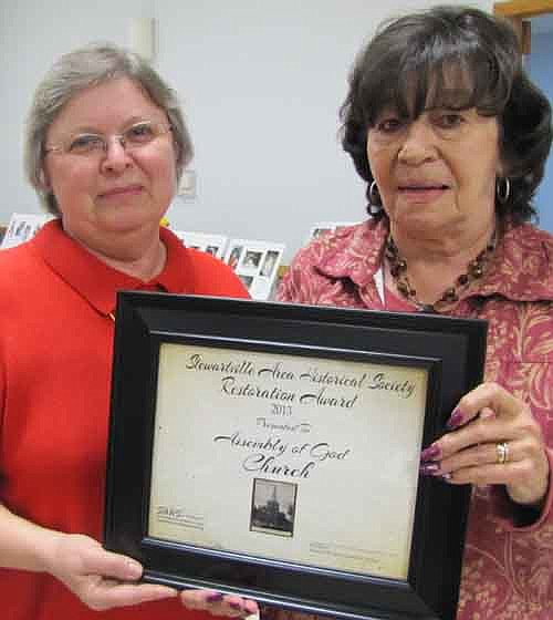 Sharon McAtee, a member of the Deacon Board of the Stewartville Assembly of God Church, right, accepts the Stewartville Area Historical Society's Restoration Award at the Society's annual meeting last Thursday, April 18. Vicki Meredith, president of the Historical Society, left, presents the award.