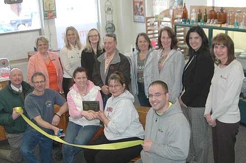 Members of the Stewartville Area Chamber of Commerce welcomed Mystic Moon Designs Antiques & Collectibles as a new chamber member with a recent official Ambassador Visit and ribbon-cutting ceremony.  Deann Stowers, Chamber President, seated at center, presents Peg Chihak a chamber plaque while Al Chihak, second from left, cuts the ribbon.  Kneeling, from left, Bill Schimmel, Al Chihak, Peg Chihak, Deann Stowers, Ryan Davis.  Standing, from left, Erika Trempe, Beth Schmidt, Melissa Sue Martin, Jimmie-John King, Judy Schroeder, Angela Carr, Margaret Nelson, Kim Brown. 