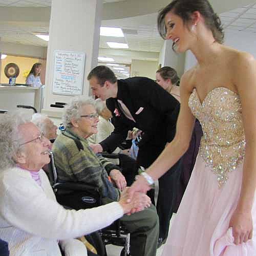Ashley Eberle, a junior at Stewartville High School, right, shakes hands with Ruth Hines at the Stewartville Care Center on Saturday, April 20. SHS students, dressed in their prom finery, met a large group of Care Center residents that day.  In the background are Lucille Laughlin, a Care Center resident, and Ethan Yost, Eberle's date for the prom.