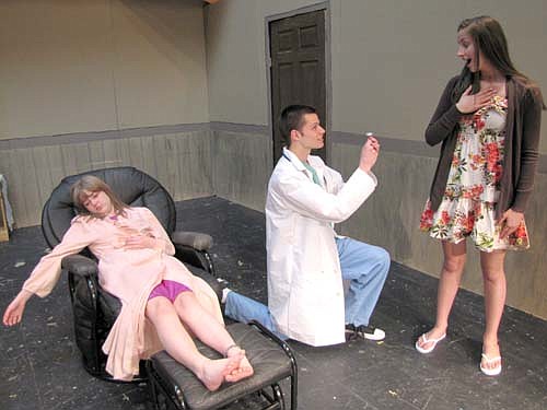 William Miller (Dr. William Bradley) pauses from his work at the hospital to propose to Adriana Nelsen-Gross (Keri) as Cassidy McCartan (Mona Jeffiers), left, is unaware of what's happening during a dress rehearsal for Stewartville High School's spring play, The Bold, the Young and the Murdered to be presented at the SHS Performing Arts Center this Friday, May 10 and Saturday, May 11 at 7 p.m. both evenings, and this Sunday, May 12 at 2 p.m. "It's funny," said Kristie Hauger, the show's director. "It's playful. It's definitely not a play that takes itself too seriously."