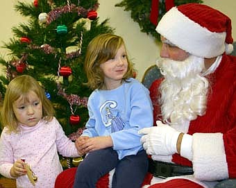 CHRISTMAS WISHES -- Megan Giordano, 6, of Stewartville, tells Santa about her Christmas wishes while holding the hand of her younger sister Kinsey, 3, during Santa's annual visit to the Stewartville Civic Center on Saturday, Dec. 1. The event is sponsored by the Stewartville Kiwanis Club. 