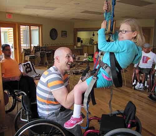 Participants at the 27th annual National Wheelchair Sports Camp at Ironwood Springs Christian Ranch near Stewartville took part in a variety of activities last week, including rope climbing, an event held inside Ironwood's Miracle Lodge on Wednesday, June 12. Emily Sullivan, 9, of LeSueur, Minn., right, holds on tight as Craig Blanchette of Battle Ground, Oregon, a staff member at the camp, assists. Campers also enjoyed a 10K race, trail riding, water skiing and more.