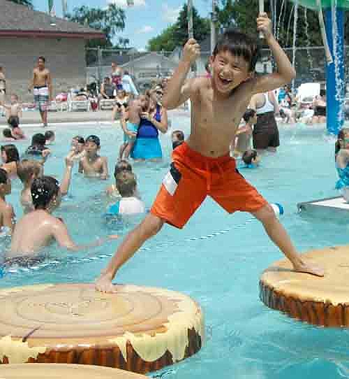 Laiken Copeman, 6, of Zumbrota, grasps the ropes as he attempts to cross the crowded Stewartville pool on a set of imitation logs on a sunny, 85-degree day last Thursday, June 27.