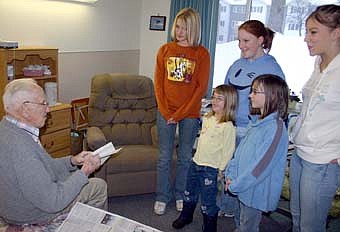Members of the Stewartville American Legion Junior Auxiliary delivered Christmas cards to veterans living at the Stewartville Care Center last week. Below, Amos Henke, who served in the U.S. Navy, opens his card as Auxiliary members from left,  Meagan Beaver, Johanna Welter, Cassie Beaver,  Amelia Welter and Rachel Beaver look on. 