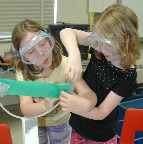 Emma Manley, left, looks especially captivated as she and her sister Addison build a rubber duck-launching device at Camp Invention at Bonner Elementary School last week. The Manley girls are from Stewar<!--1up-20-->tville.