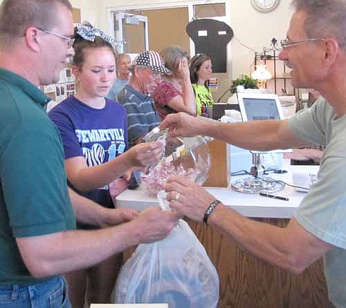 Al Chihak of Mystic Moon Antiques & Collectibles, right, completes a transaction with Mike Brainard and his daughter Mikayla of Stewartville, who were part of the Cash Mob that visited Mystic Moon last Thursday, July 18.